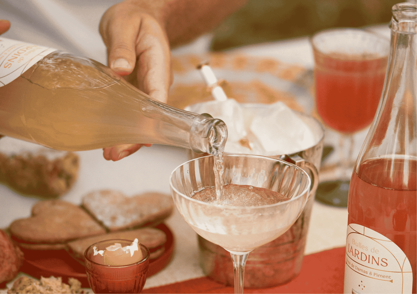 une main tient une bouteille de petillant sans alcool jardins en remplissant un verre