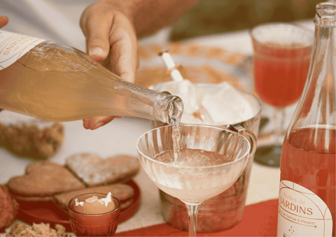 une main tient une bouteille de petillant sans alcool jardins en remplissant un verre