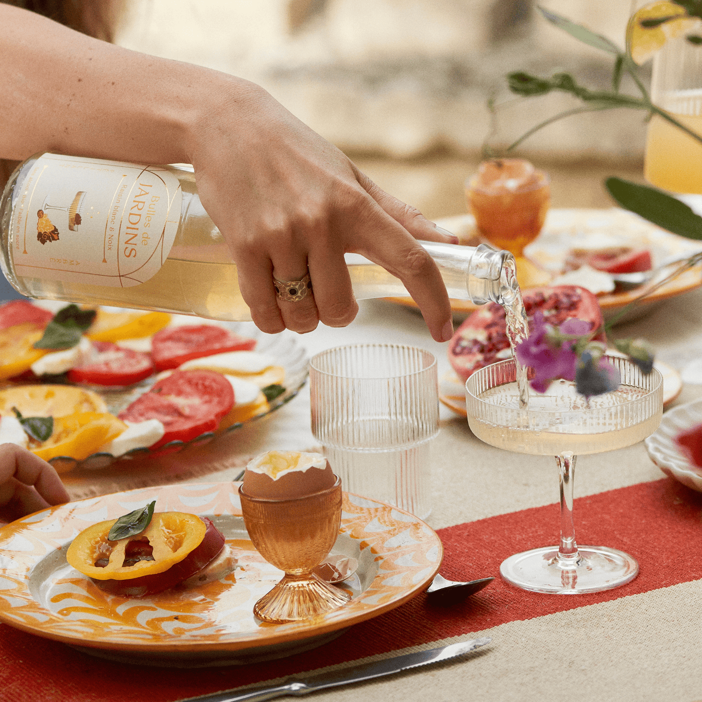 
                  
                    Bouteille de Bulles de Jardins Raisin Noix, cocktail sans alcool prêt à boire, bio et faible en sucre en train d'être versée.
                  
                